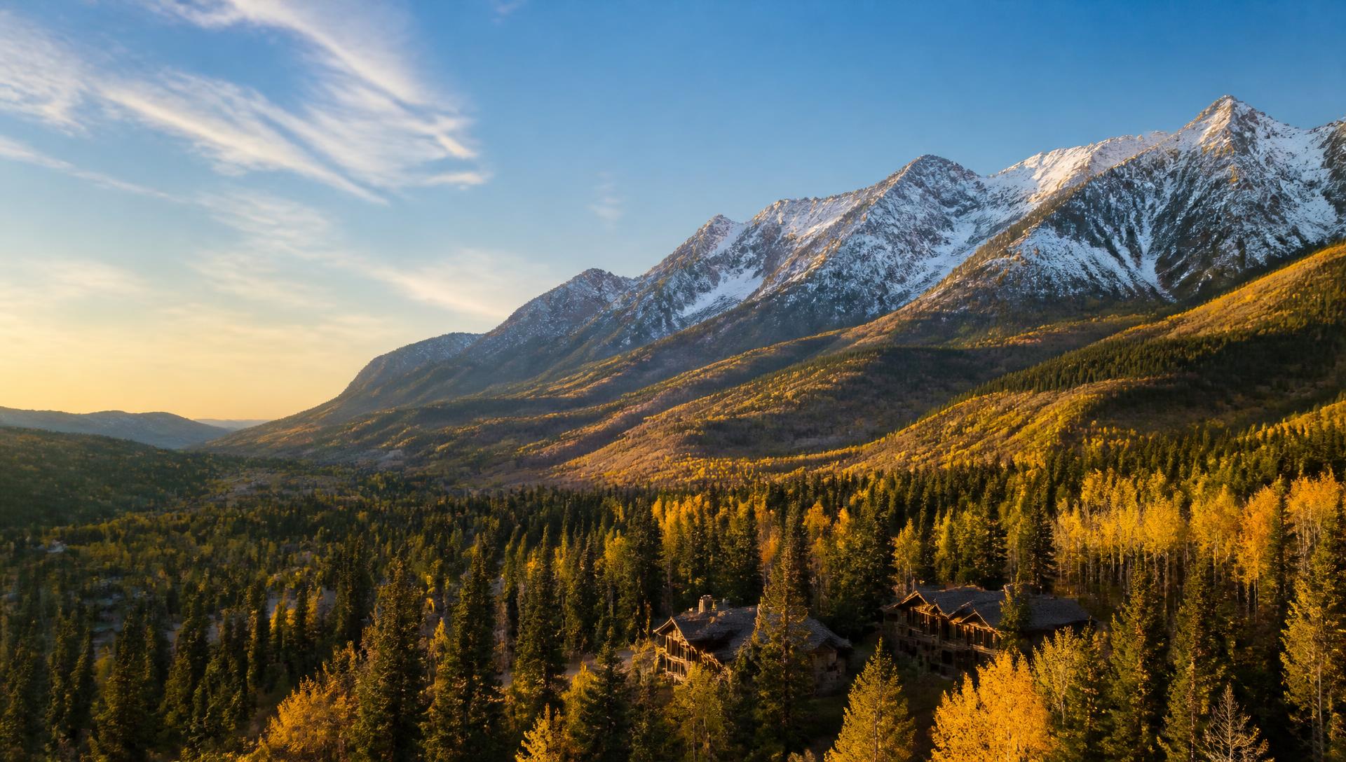 Vail Valley, Colorado at golden hour with snow-dusted peaks above aspen groves and mountain homes